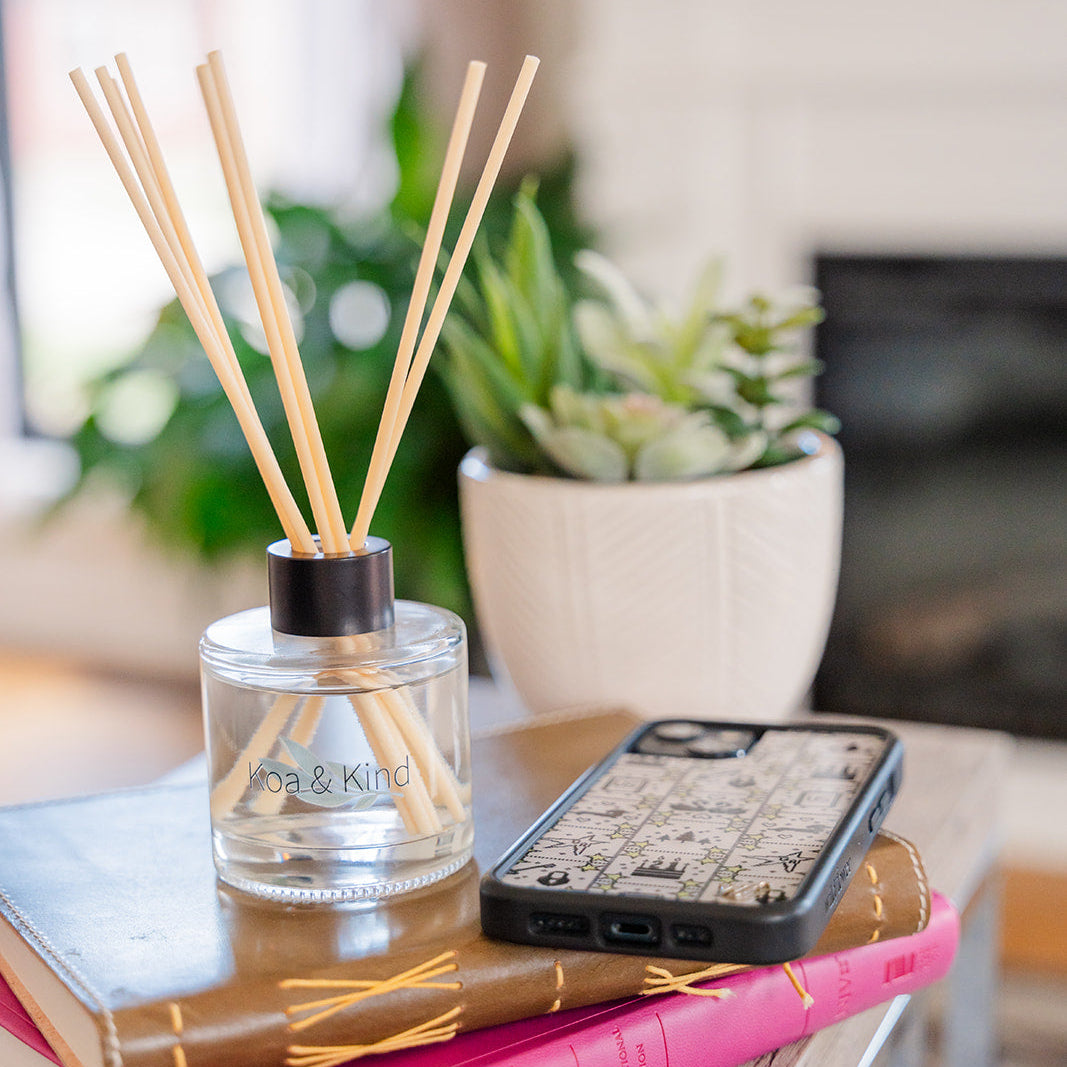 Diffuser with wooden sticks on books with a phone and plant in the background