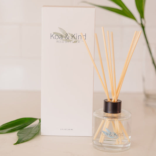 Koa & Kind diffuser with packaging and green leaves on a light background